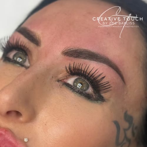Fresh bold powder brows on fair skin showing dramatic saturation with strong defined arch and crisp edges coordinated with full lash extensions and eyeliner