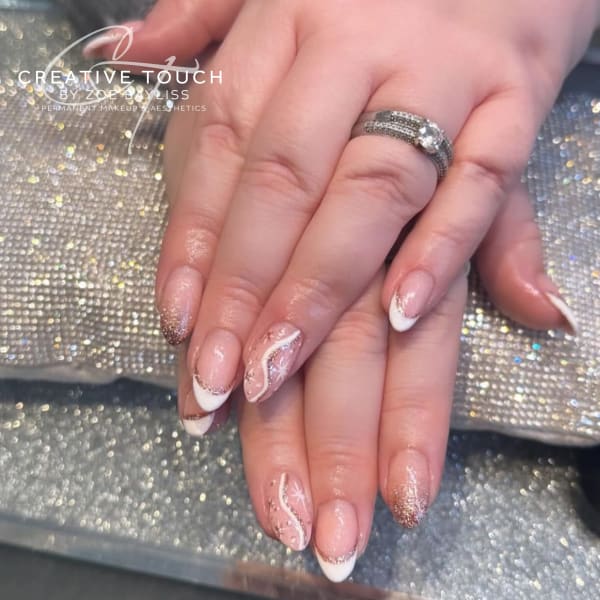 Close-up of client's nails featuring a nude base coat topped with shimmering glitter, sprinkled with tiny silver stars.