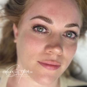 Portrait of a client after eyebrow microblading, showing the detail of the realistic brow strokes and micropigmentation behind