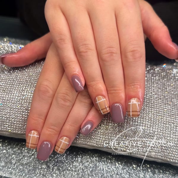 A close-up of hands with oval nails featuring a warm-toned tartan pattern in shades of brown, beige, and taupe.