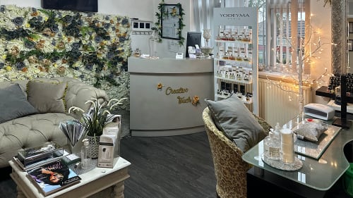 Inside the Creative Touch salon with the reception desk ahead and the nail salon table to the right. A sofa and small coffee table is to the left with beauty magazines placed on it.