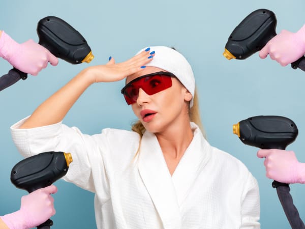 A young woman dressed in a robe, wearing protective laser glasses looking confused. Multiple laser hair devices are pointing at her from different directions.