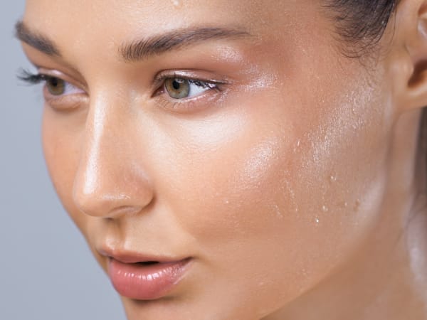 Close up profile of a young woman with healthy glowing skin. Beads of sweat can be seen sitting on the surface of her skin - a sign of an intact skin barrier