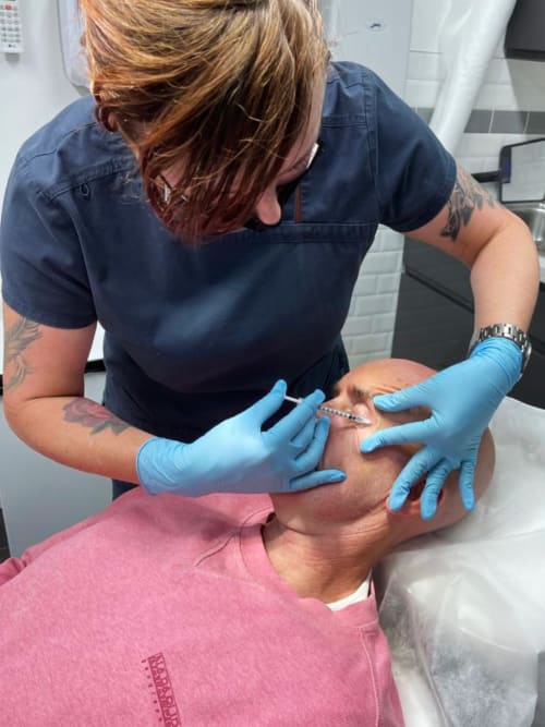 Zoe Bayliss administering Botox injection around the eyes of a client to reduce lines and wrinkles.