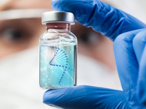 Polynucleotides illustrated by a scientist holding a vial of blue liquid containing a DNA helix. Short field of view with the focus on the ampoule.