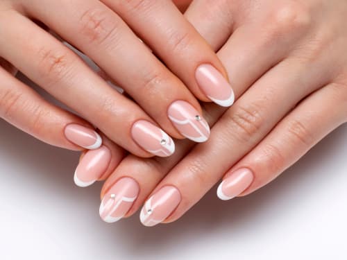 Close up of oval French tip nails with a modern geometric design and subtle crystal highlights
