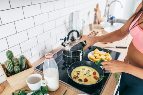 A slim woman cooking a low-carb omelette for a meal.