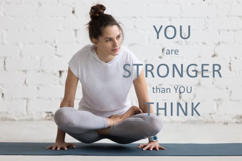 Motivational poster: a young woman holds herself in the air during yoga. In the foreground are the words: 'you are stronger than you think'.