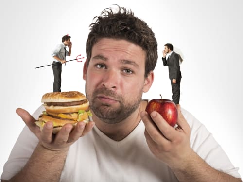 A slightly overweight man struggles with his internal voices whilst weighing up the healthy (apple) versus unhealthy (fast-food burgers) food choices.