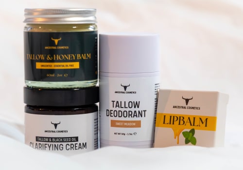Collection of handmade tallow-based skincare products, including balms, creams, cleansers, and deodorants