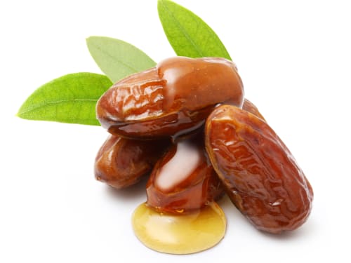 Jojoba oil drizzled over jojoba seeds on a white background