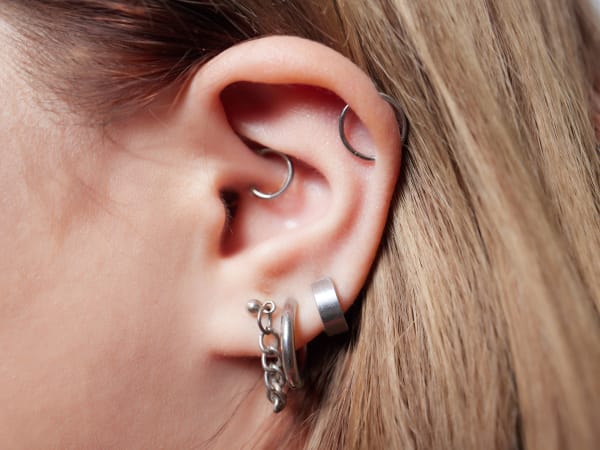 Ear with multiple piercings featuring mixed hoop and chain jewellery.