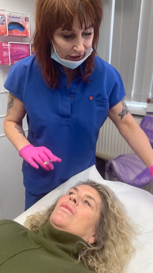 Zoe Bayliss stands beside the client ready to inject the mesotherapy dissolve. The client is laying on the treatment table.
