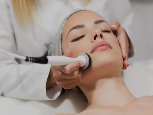 An attractive lady receiving radio frequency skin tightening treatment to her cheeks